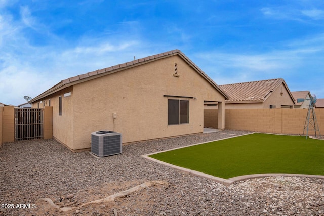 back of house featuring a fenced backyard, stucco siding, central AC, and a tiled roof