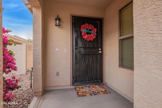 property entrance with stucco siding and fence