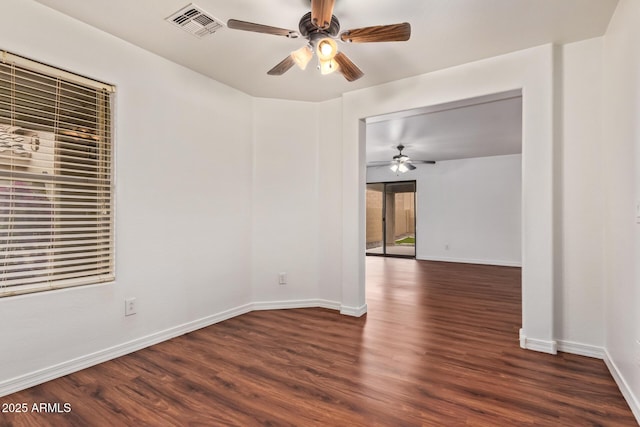 unfurnished room featuring a ceiling fan, dark wood-type flooring, baseboards, and visible vents