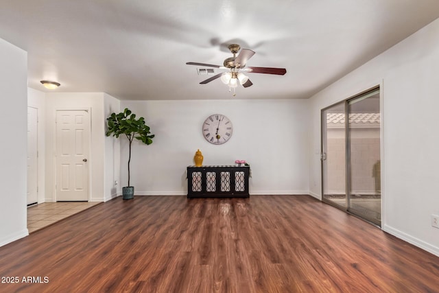 spare room featuring a ceiling fan, visible vents, baseboards, and wood finished floors