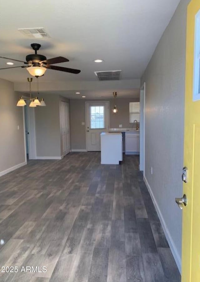 unfurnished living room featuring ceiling fan, sink, and dark wood-type flooring