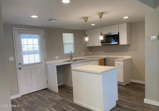 kitchen featuring sink, a kitchen island, dark hardwood / wood-style flooring, pendant lighting, and white cabinets