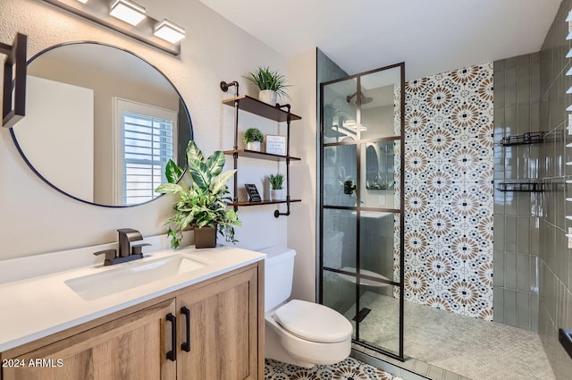 bathroom featuring a tile shower, tile patterned flooring, vanity, and toilet