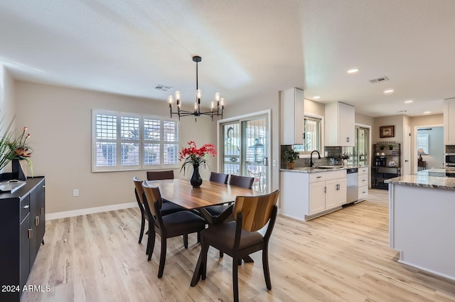 dining room featuring plenty of natural light, light hardwood / wood-style floors, sink, and an inviting chandelier