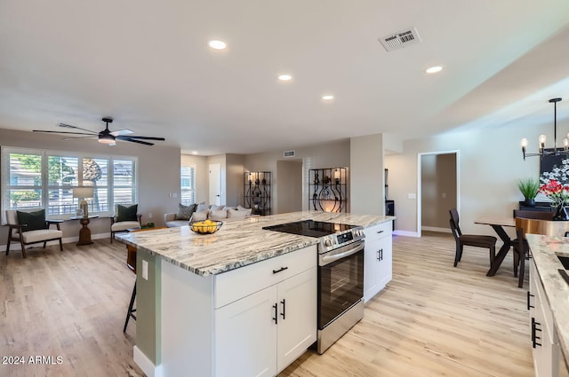 kitchen with stainless steel range with electric stovetop, pendant lighting, a center island, light stone countertops, and white cabinetry