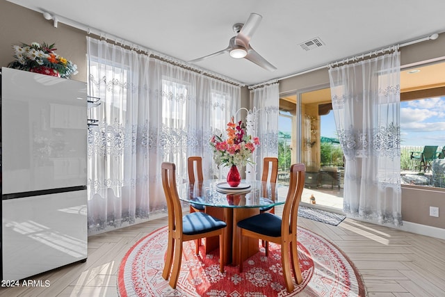 dining area featuring a healthy amount of sunlight, ceiling fan, and light parquet flooring