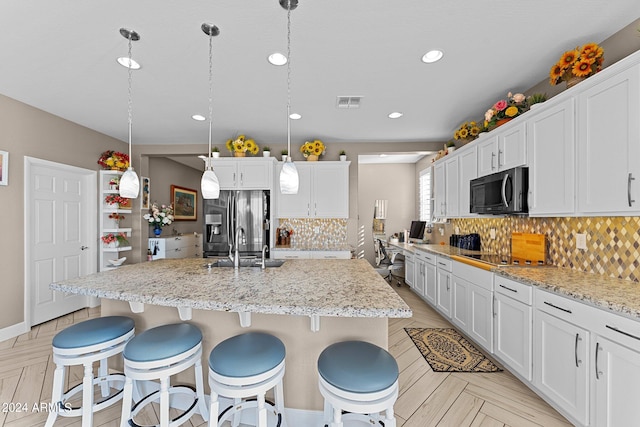 kitchen featuring backsplash, appliances with stainless steel finishes, a kitchen island with sink, white cabinetry, and hanging light fixtures