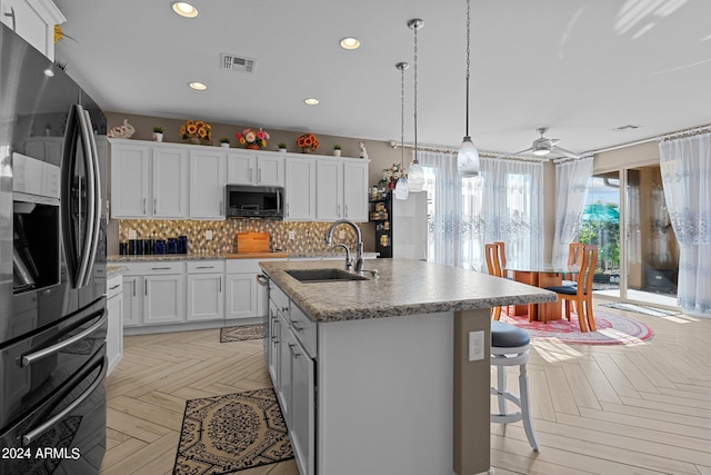 kitchen with white cabinetry, sink, light parquet floors, a kitchen island with sink, and black fridge with ice dispenser