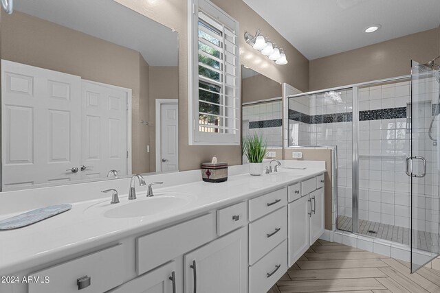 bathroom featuring walk in shower and dual bowl vanity