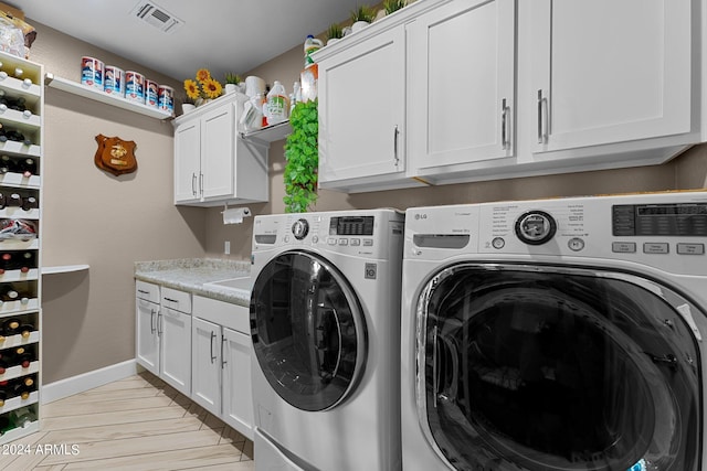 laundry area with cabinets, light hardwood / wood-style floors, and washer and dryer