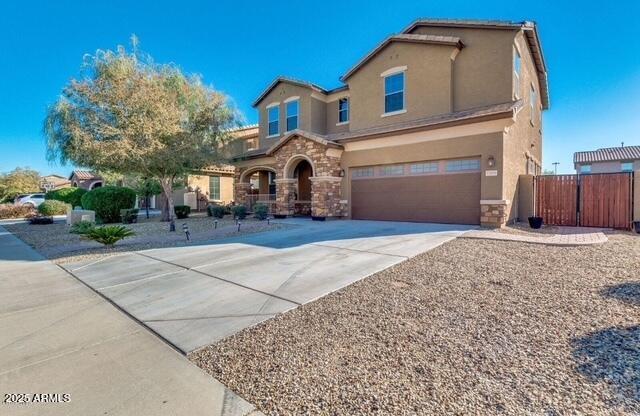15105 W Glenrosa Ave, Goodyear, AZ 85395 - view of front of house with a garage, stucco siding, stone siding, concrete driveway, and a gate