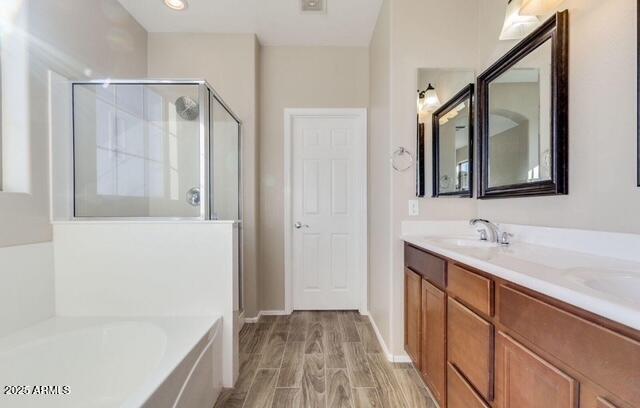 15105 W Glenrosa Ave, Goodyear, AZ 85395 - bathroom featuring a stall shower, a bath, double vanity, wood finished floors, and baseboards
