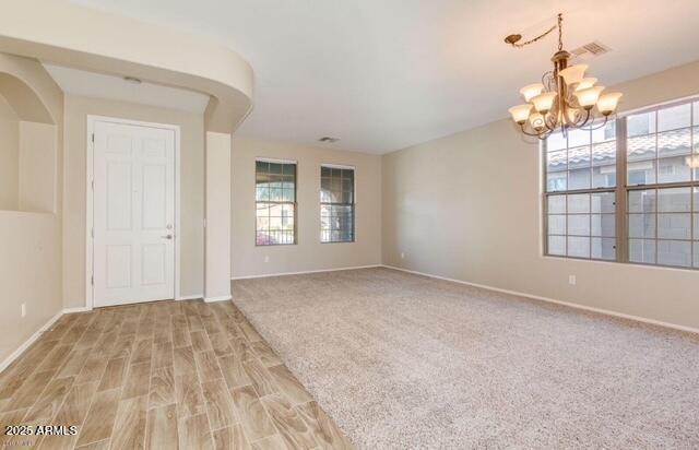 15105 W Glenrosa Ave, Goodyear, AZ 85395 - unfurnished room featuring a chandelier, baseboards, and light wood finished floors