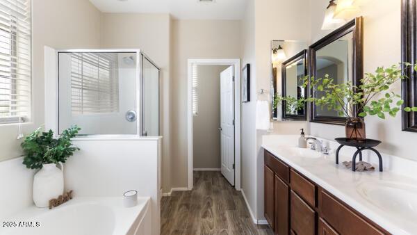 15105 W Glenrosa Ave, Goodyear, AZ 85395 - full bath featuring a shower stall, double vanity, wood finished floors, a bath, and baseboards