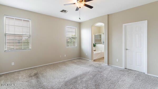 15105 W Glenrosa Ave, Goodyear, AZ 85395 - unfurnished bedroom with carpet floors, arched walkways, baseboards, and ensuite bathroom