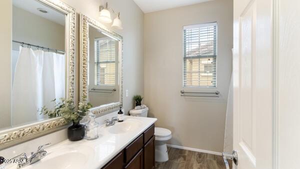 15105 W Glenrosa Ave, Goodyear, AZ 85395 - bathroom featuring double vanity, toilet, wood finished floors, and baseboards