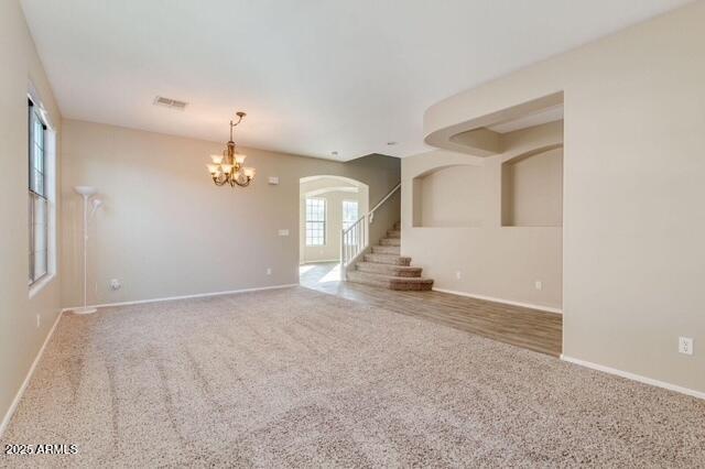 15105 W Glenrosa Ave, Goodyear, AZ 85395 - unfurnished living room with a chandelier, arched walkways, carpet, and baseboards