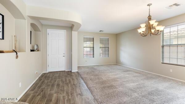 15105 W Glenrosa Ave, Goodyear, AZ 85395 - spare room with a chandelier, baseboards, wood finished floors, and arched walkways