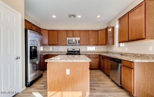 15105 W Glenrosa Ave, Goodyear, AZ 85395 - kitchen featuring stainless steel appliances, light wood-type flooring, brown cabinets, a kitchen island, and recessed lighting