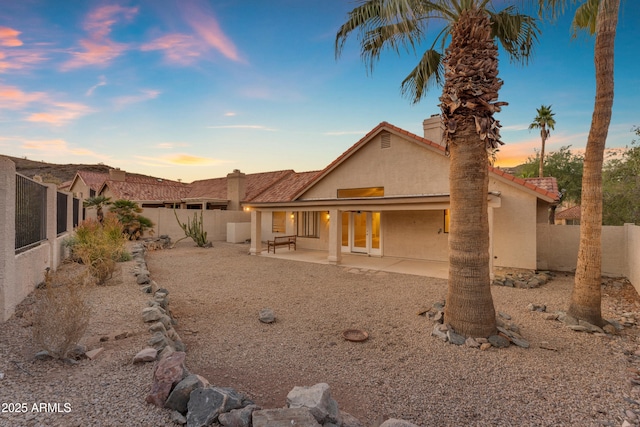 15232 S 36th Pl, Phoenix, AZ 85044 - back of property at dusk with stucco siding, a chimney, a fenced backyard, a patio area, and a tiled roof