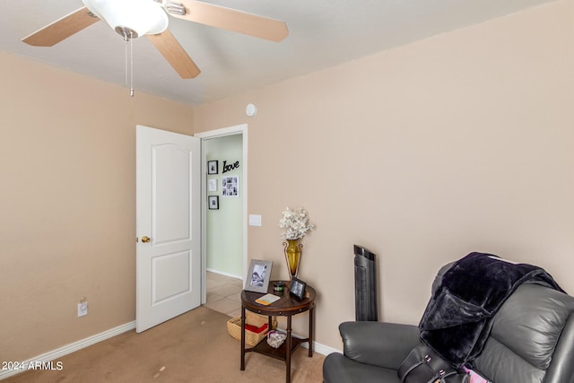 living area featuring light colored carpet and ceiling fan