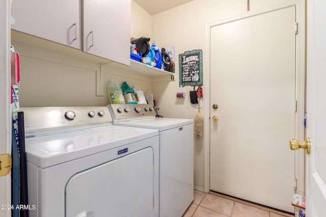 clothes washing area with light tile patterned floors, cabinets, and washer and clothes dryer