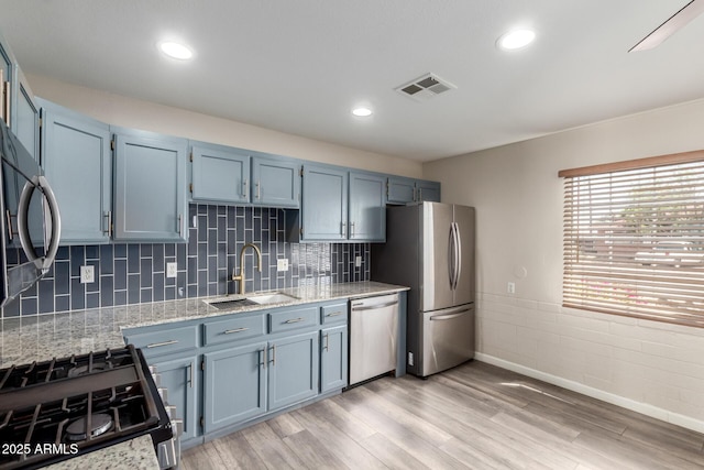 2914 W Marlette Ave, Phoenix, AZ 85017 - kitchen with light stone countertops, appliances with stainless steel finishes, a sink, blue cabinetry, and light wood-style flooring