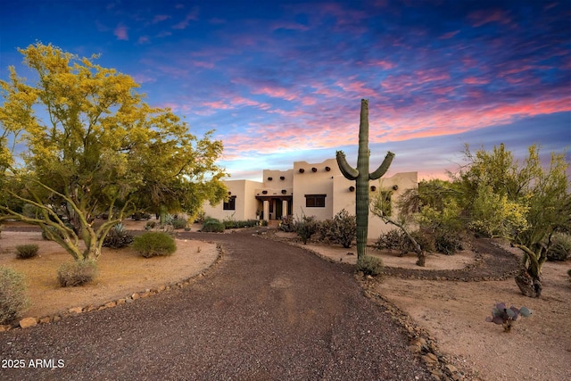adobe home featuring stucco siding and curved driveway
