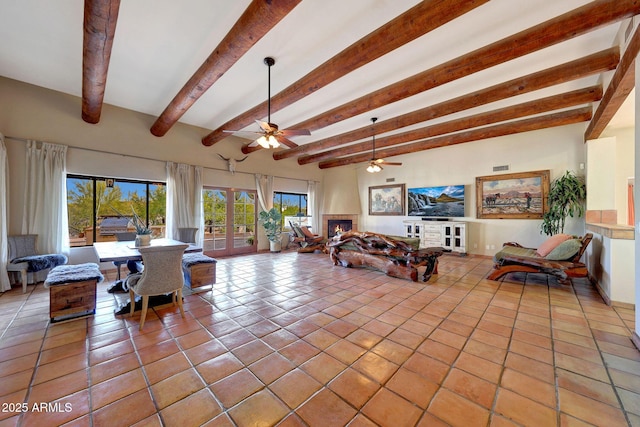 dining area with beam ceiling, light tile patterned floors, ceiling fan, and a large fireplace