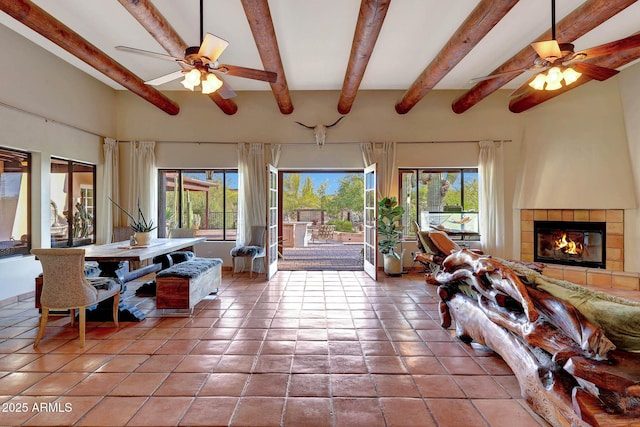 living room featuring ceiling fan, beamed ceiling, a tile fireplace, and tile patterned flooring