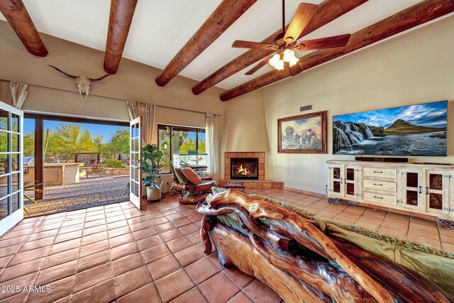 living room featuring beam ceiling, tile patterned floors, a ceiling fan, and a fireplace