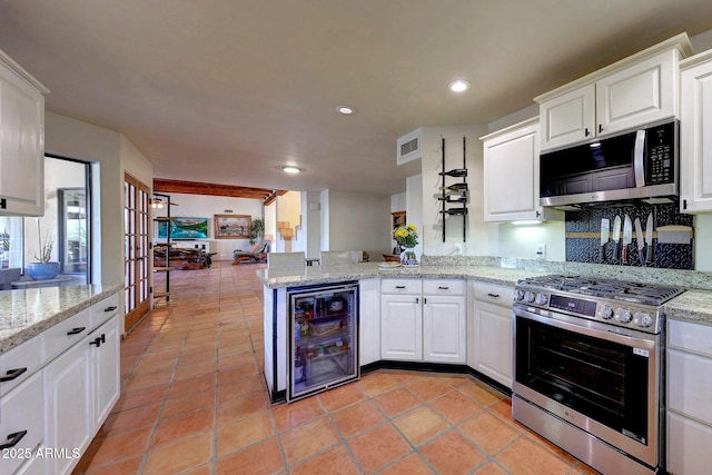 kitchen with appliances with stainless steel finishes, beverage cooler, white cabinetry, recessed lighting, and a peninsula