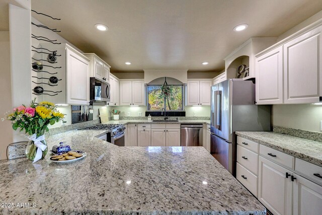 kitchen with appliances with stainless steel finishes, a sink, white cabinetry, light stone countertops, and recessed lighting