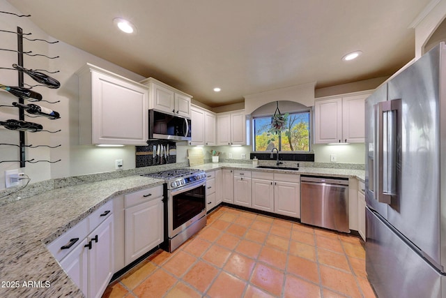 kitchen with stainless steel appliances, a sink, white cabinets, recessed lighting, and light stone countertops