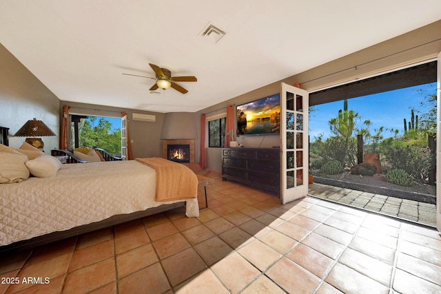 tiled bedroom featuring access to exterior, a glass covered fireplace, and ceiling fan