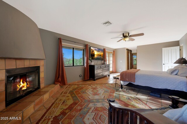 tiled bedroom featuring a fireplace and a ceiling fan
