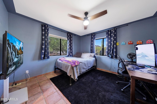 bedroom with an office area, ceiling fan, and stone tile flooring