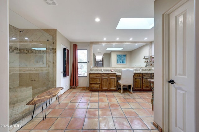full bathroom with a skylight, tile patterned flooring, tiled shower, vanity, and recessed lighting