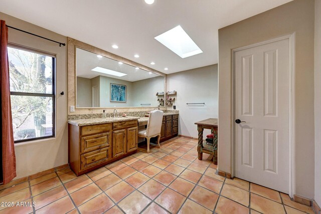 bathroom featuring a skylight, vanity, recessed lighting, tile patterned floors, and decorative backsplash