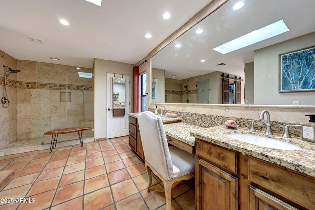 full bathroom featuring a skylight, a tile shower, tile patterned floors, vanity, and recessed lighting