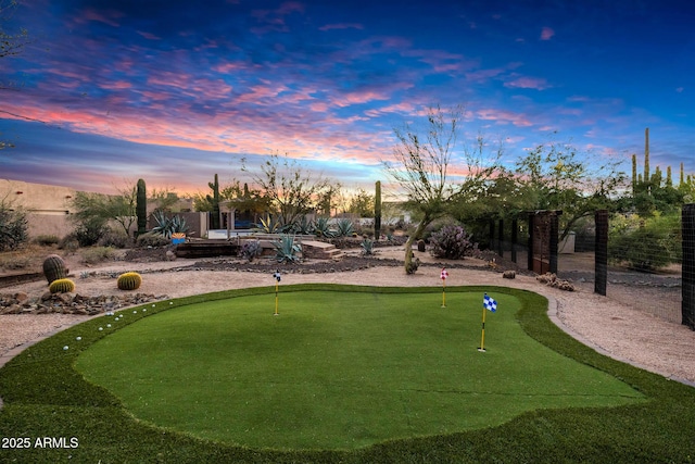 view of property's community featuring an area to practice putting and fence