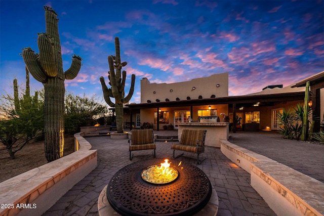 patio terrace at dusk featuring an outdoor fire pit and an outdoor kitchen
