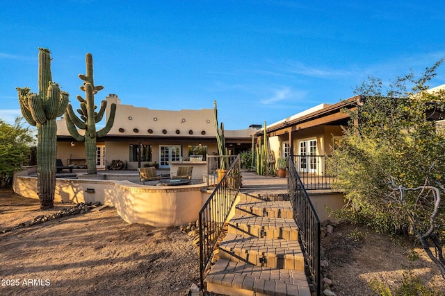 rear view of house with french doors, a patio, and stucco siding
