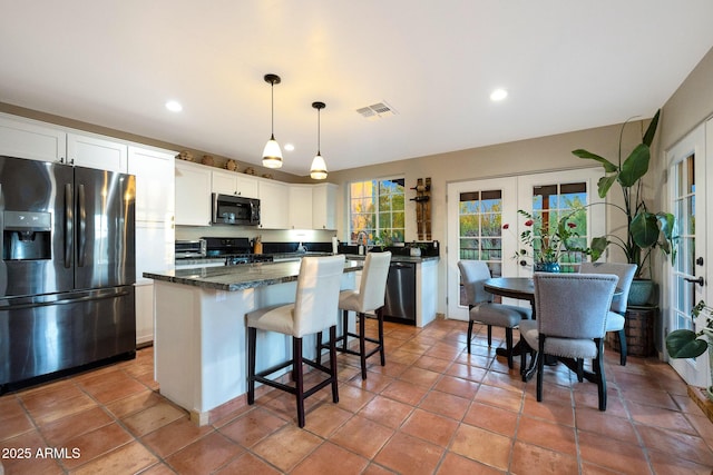 kitchen with fridge with ice dispenser, dishwashing machine, french doors, gas range oven, and a kitchen island