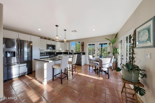kitchen featuring stainless steel appliances, french doors, a center island, white cabinets, and a kitchen breakfast bar