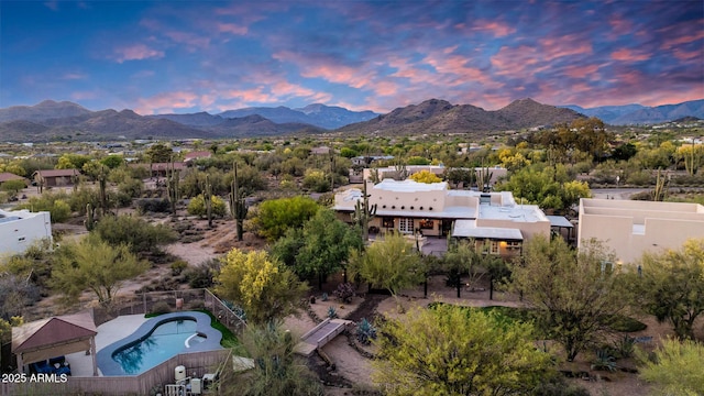 aerial view at dusk of a mountain view and view of pool
