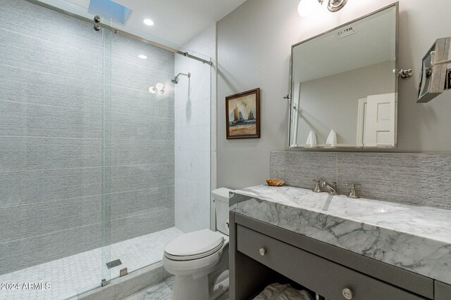 bathroom featuring a shower with shower door, vanity, toilet, and tasteful backsplash