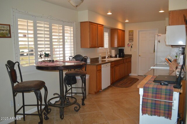 221 N Mountain Rd, Apache Junction, AZ 85120 - kitchen featuring white appliances, a sink, brown cabinetry, light tile patterned flooring, and dark countertops