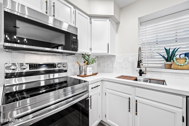 kitchen with white cabinets, backsplash, appliances with stainless steel finishes, and sink