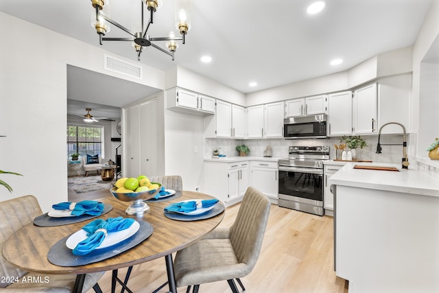 dining room featuring light hardwood / wood-style floors, ceiling fan with notable chandelier, and sink